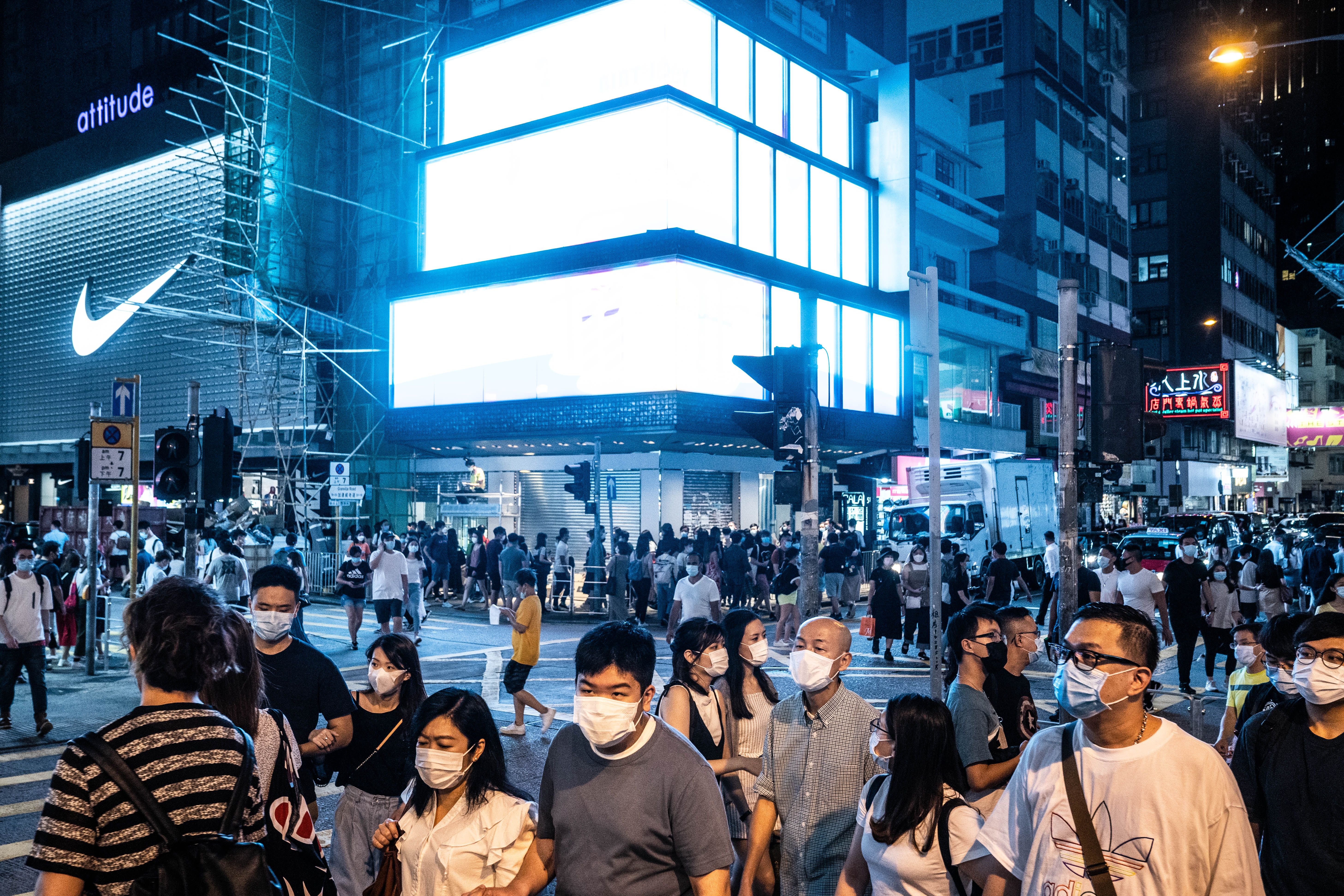 政府昨日放寬部分防疫措施，食肆容許每檯食客增至四人，遊戲機中心及遊樂場所等處所獲准重開。戴著口罩的市民紛紛出街探食。（彭博社）